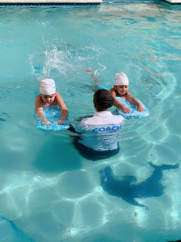 A WAVE coach in the pool with two young swimmers